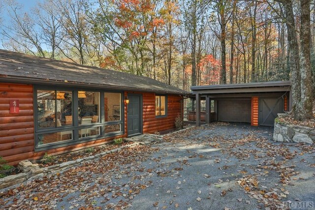 exterior space with a garage, a carport, and an outbuilding