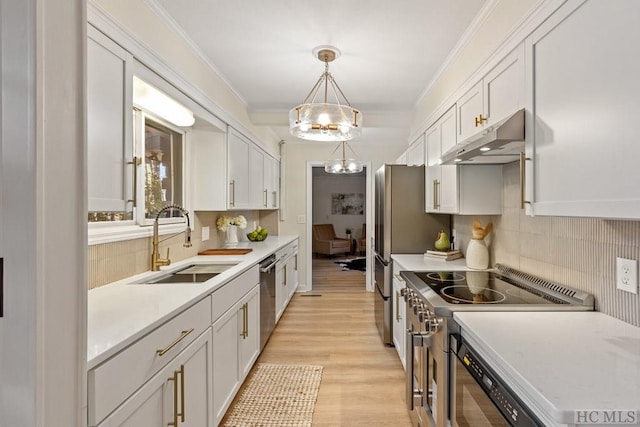 kitchen featuring sink, ornamental molding, appliances with stainless steel finishes, white cabinets, and pendant lighting