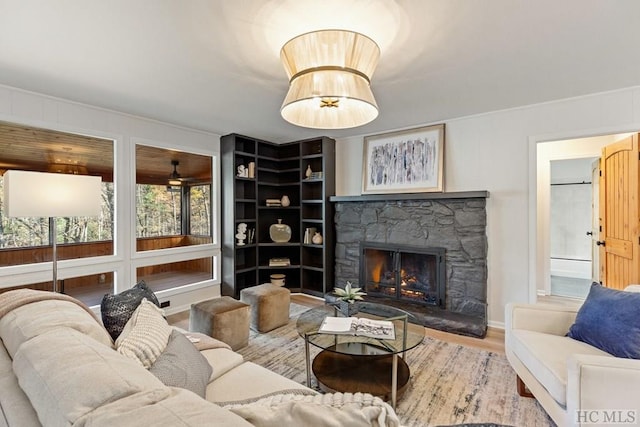 living room featuring wood-type flooring, a stone fireplace, and built in shelves