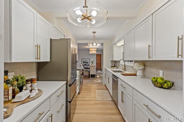 kitchen with sink, white cabinetry, tasteful backsplash, appliances with stainless steel finishes, and pendant lighting