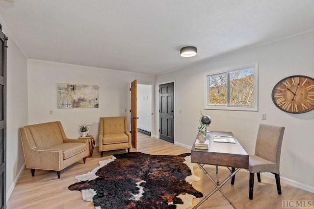 home office featuring baseboard heating, a barn door, and light hardwood / wood-style floors