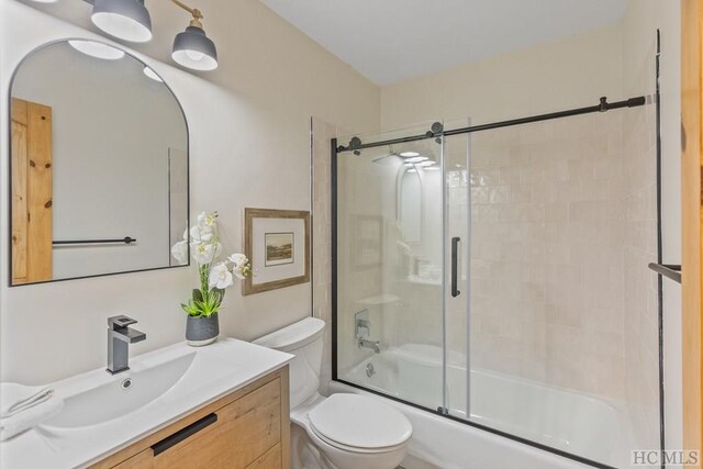 full bathroom with vanity, shower / bath combination with glass door, and toilet