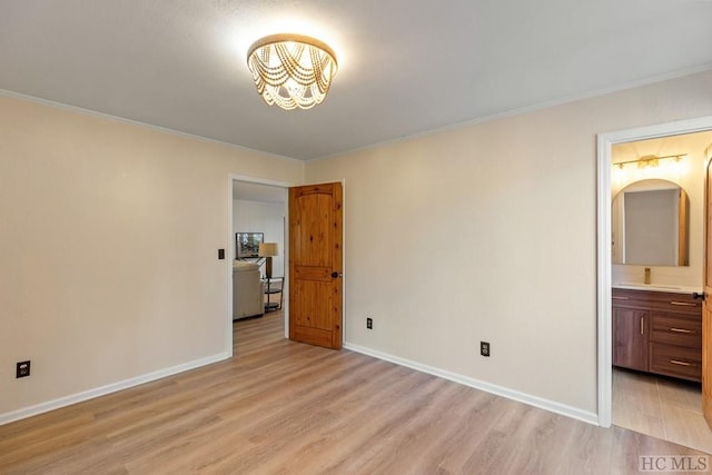 unfurnished bedroom featuring ornamental molding, light hardwood / wood-style floors, and ensuite bath