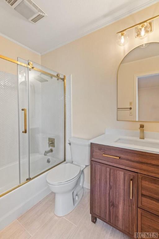 full bathroom with tile patterned floors, toilet, bath / shower combo with glass door, ornamental molding, and vanity