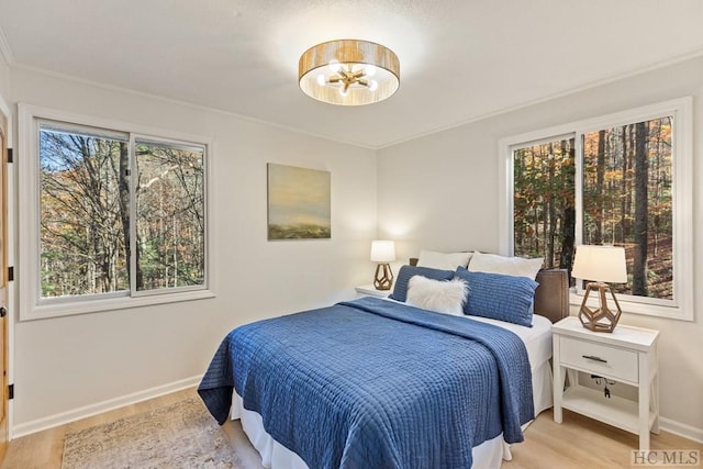 bedroom with multiple windows, ornamental molding, and light hardwood / wood-style floors