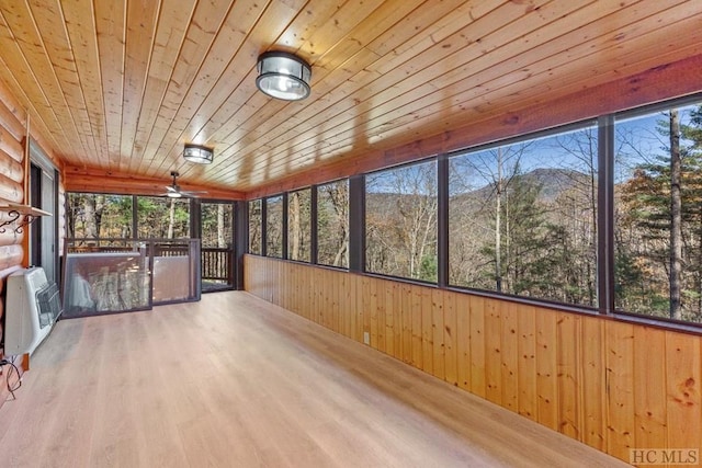 unfurnished sunroom featuring ceiling fan, heating unit, a wealth of natural light, and wood ceiling