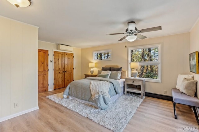 bedroom featuring ceiling fan, two closets, light hardwood / wood-style floors, and an AC wall unit