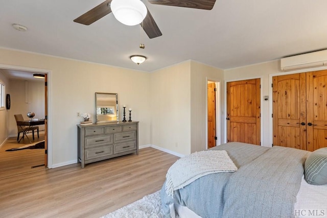 bedroom with a wall mounted air conditioner, light hardwood / wood-style flooring, and ceiling fan