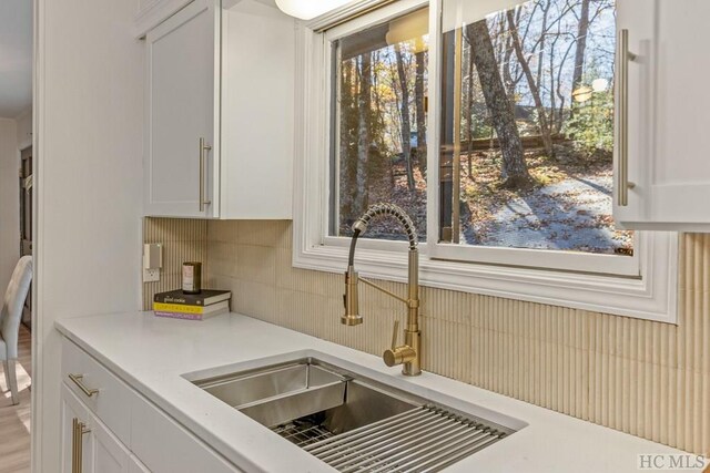 kitchen featuring tasteful backsplash, sink, and white cabinets