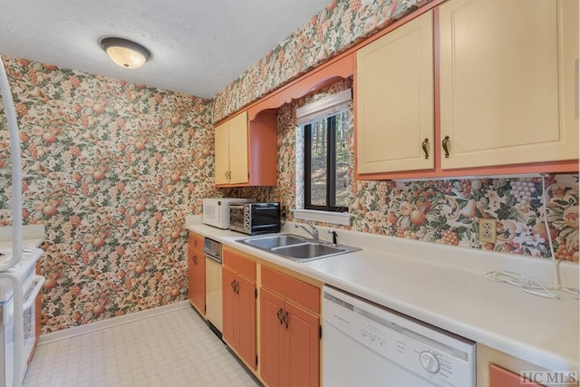 kitchen with white dishwasher, sink, and a textured ceiling