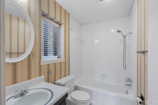 full bathroom with toilet, a textured ceiling, vanity, wooden walls, and tiled shower / bath combo