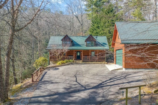 log home featuring covered porch and a garage