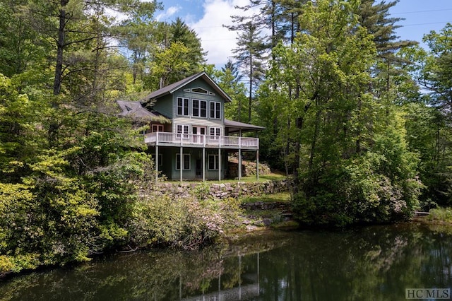 back of property featuring a deck with water view