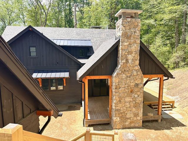 298 Pine Forest Rd, Sapphire, NC 28774 - back of house with board and batten siding, a shingled roof, a standing seam roof, a chimney, and a metal roof