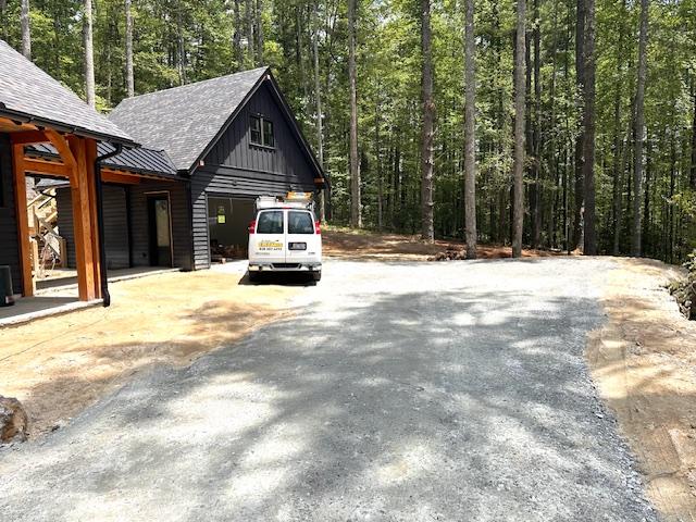 298 Pine Forest Rd, Sapphire, NC 28774 - view of side of home featuring asphalt driveway, board and batten siding, a wooded view, and roof with shingles