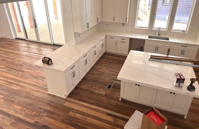 298 Pine Forest Rd, Sapphire, NC 28774 - kitchen with dark wood-type flooring, white cabinetry, and light stone counters