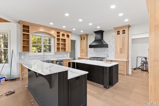 kitchen with premium range hood, a breakfast bar, a healthy amount of sunlight, and a center island with sink