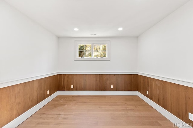 empty room with wooden walls and light hardwood / wood-style flooring