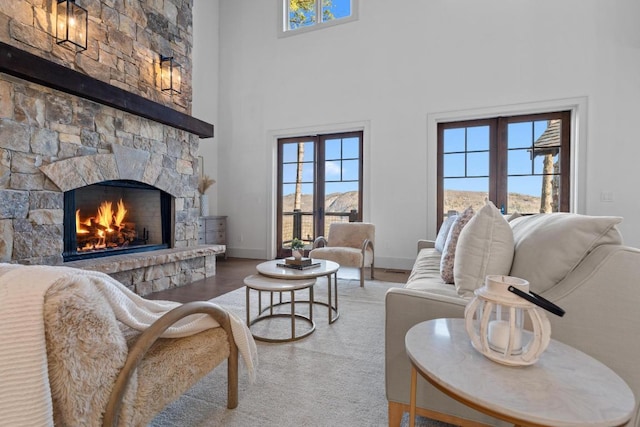 living area featuring wood finished floors, a high ceiling, a fireplace, and a healthy amount of sunlight