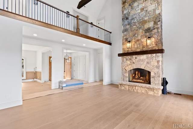 unfurnished living room with a towering ceiling, a fireplace, and light hardwood / wood-style floors