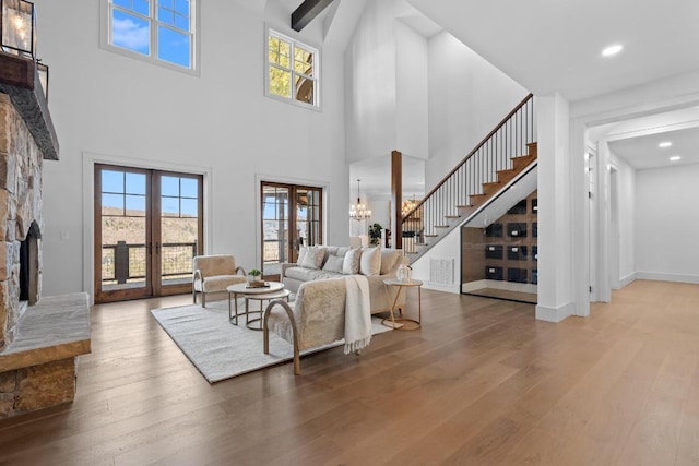 living room featuring french doors, a stone fireplace, wood finished floors, and stairway