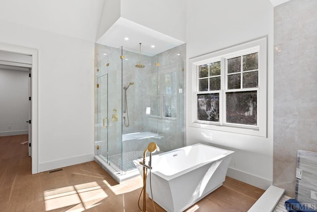 bathroom with hardwood / wood-style flooring, vaulted ceiling, and shower with separate bathtub