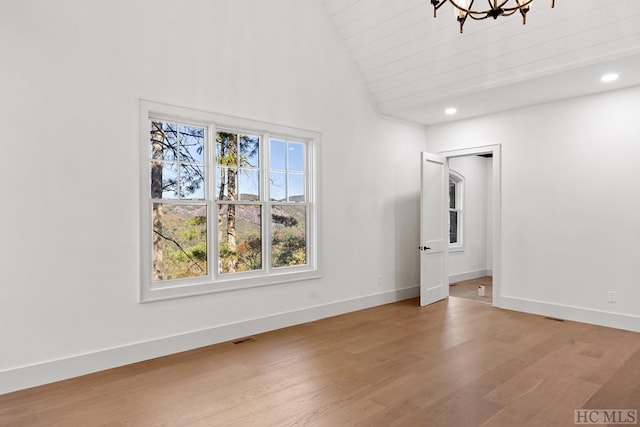 unfurnished living room with high vaulted ceiling, light hardwood / wood-style floors, and a notable chandelier