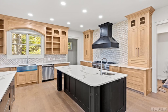 kitchen featuring sink, appliances with stainless steel finishes, an island with sink, light brown cabinetry, and custom exhaust hood