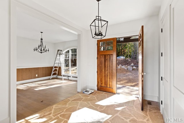 foyer with wood-type flooring, wooden walls, and a chandelier