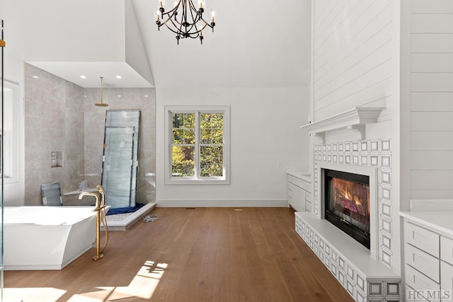 unfurnished living room with an inviting chandelier, hardwood / wood-style flooring, and high vaulted ceiling