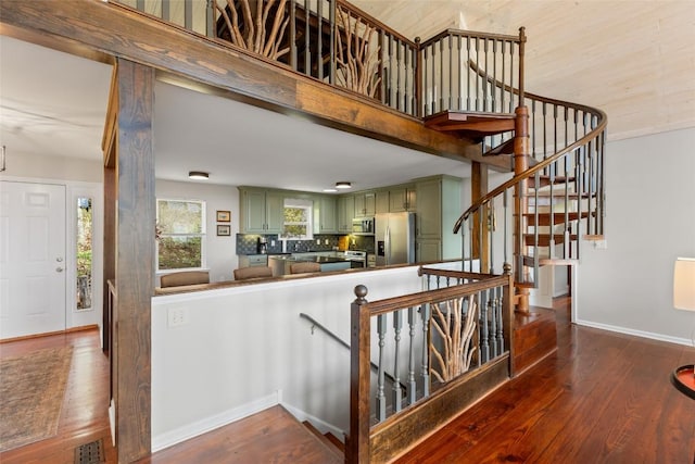 staircase with baseboards, visible vents, and hardwood / wood-style floors