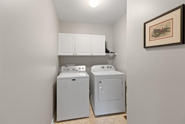 clothes washing area featuring baseboards, cabinet space, and washing machine and dryer