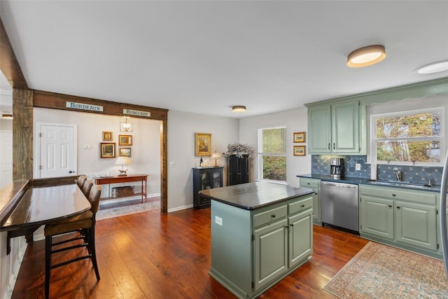 kitchen with dark countertops, a center island, stainless steel dishwasher, dark wood finished floors, and green cabinetry