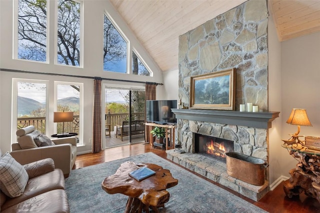 living area featuring a stone fireplace, baseboards, wood finished floors, and wooden ceiling