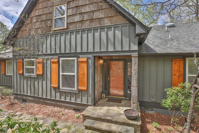 doorway to property featuring board and batten siding, crawl space, and a shingled roof