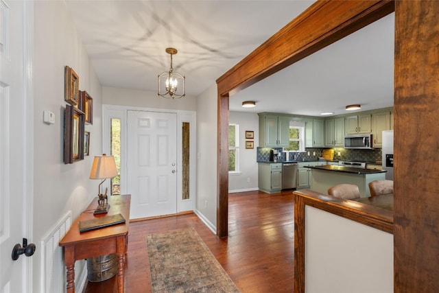 foyer entrance with baseboards, dark wood-style floors, and a chandelier