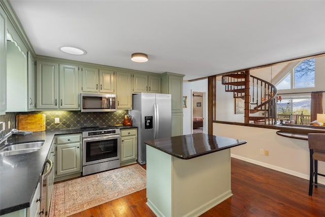kitchen featuring dark countertops, appliances with stainless steel finishes, a sink, dark wood finished floors, and backsplash