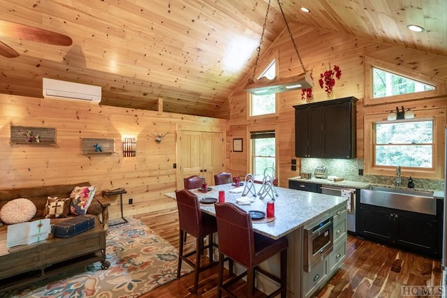 kitchen featuring a wall mounted AC, a kitchen island, wood walls, sink, and light stone counters