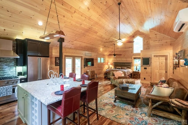 kitchen featuring a breakfast bar, high quality appliances, pendant lighting, wood walls, and light stone countertops