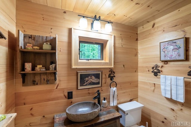 bathroom featuring toilet, vanity, wood ceiling, and wood walls