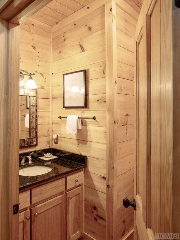 bathroom with vanity, wood ceiling, and wood walls