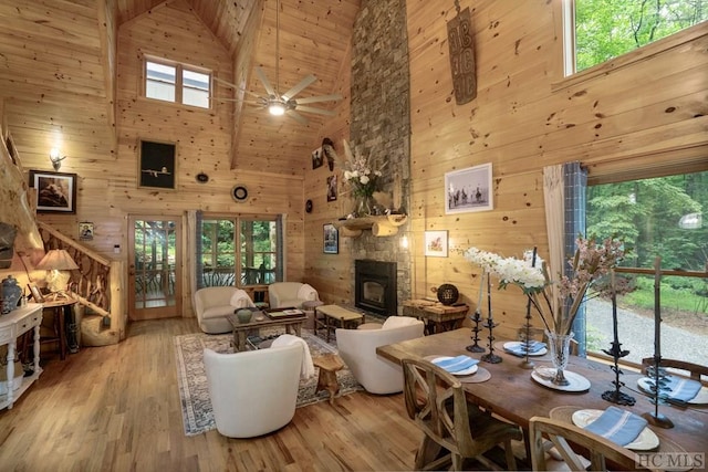 living room with hardwood / wood-style flooring, wooden walls, and a stone fireplace