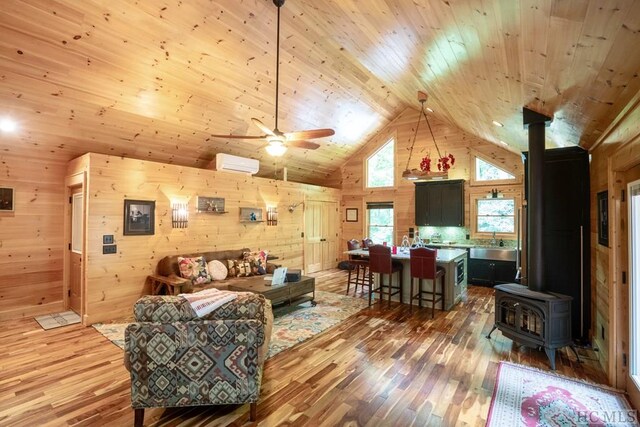 living room featuring a wall unit AC, a wood stove, and wooden walls