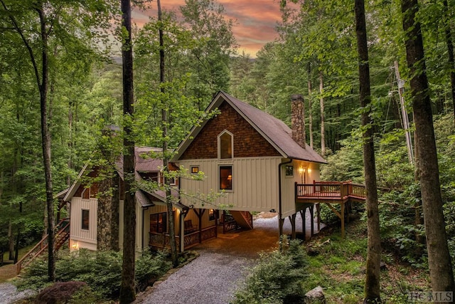 back house at dusk featuring a deck and a carport