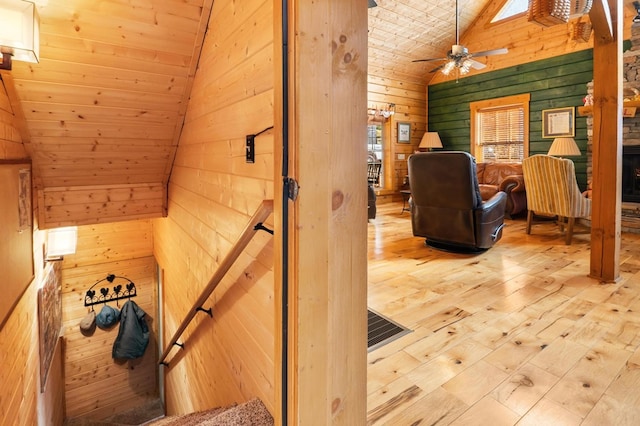 staircase with vaulted ceiling, hardwood / wood-style floors, wooden walls, and ceiling fan