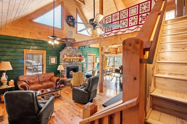 living room with a healthy amount of sunlight, ceiling fan, wood walls, and a fireplace