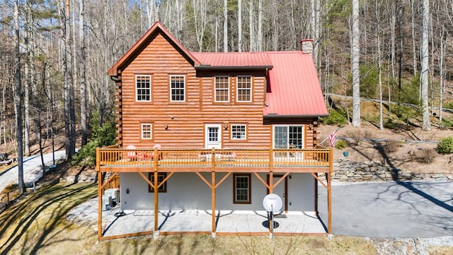 rear view of house with a wooden deck and a patio area