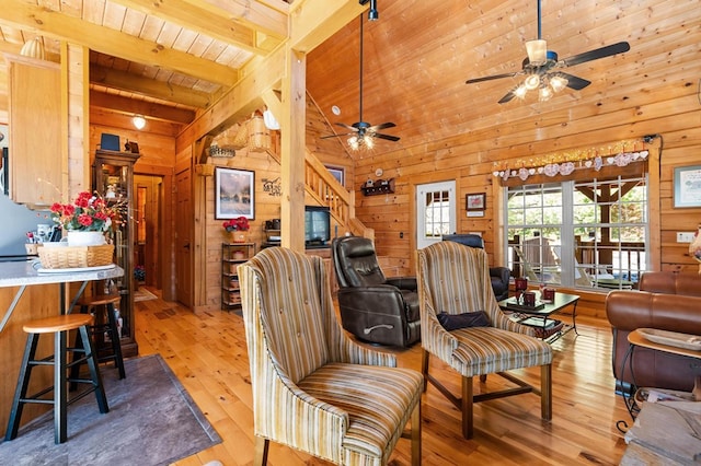 living room with light hardwood / wood-style flooring, wooden walls, wood ceiling, and beam ceiling