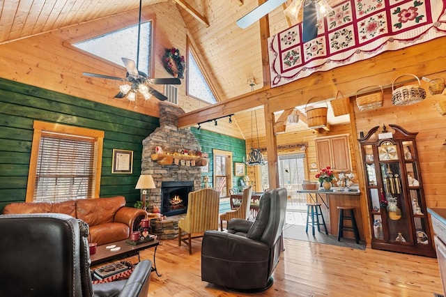 living room with light hardwood / wood-style flooring, wooden walls, wood ceiling, and a stone fireplace