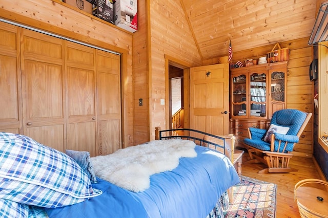 bedroom featuring hardwood / wood-style floors, wood walls, a closet, and lofted ceiling